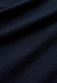 Tmavě námořnická pletenina s hladkým povrchem, s jemnými horizontálními pruhy a drobnými záhyby, které vytvářejí hloubku a rozměr.