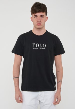 T-shirt in cotone nero con maniche corte e colletto rotondo. Presenta la scritta bianca "POLO RALPH LAUREN" stampata sul davanti. Texture liscia.
