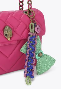 Różowa pikowana skórzana torebka na łańcuszku z dekoracyjnymi charmsami, w tym zieloną kokardą i plecionymi kolorowymi akcentami. Złote detale.