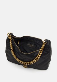 Czarna pikowana torebka wykonana z materiału z recyklingu, z paskiem na złoty łańcuszek i ozdobnym złotym elementem dekoracyjnym wewnątrz.