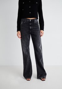 High-waisted, wide-leg black jeans in soft, slightly distressed denim with a subtle wash. Features front pockets and a standard button closure.
