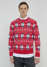 Pull en tricot rouge avec des motifs d'ours polaires portant des chapeaux, complété par des motifs de flocons de neige blancs et des accents bleu marine.