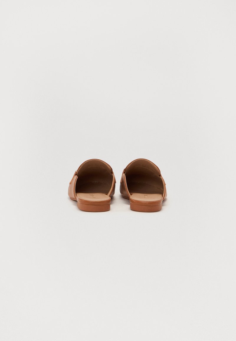 Sandales marron en cuir lisse, avec un dos ouvert et une semelle plate. Design simple avec des détails de couture minimaux.