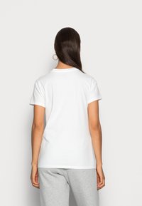 Camiseta de algodón blanca con mangas cortas, escote redondo y un corte relajado. La vista trasera muestra una textura suave y un diseño sencillo.