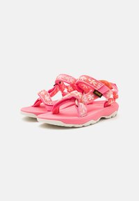 Sandalias infantiles rosas con correas ajustables con estampado de flores y suelas de goma blancas, en un ángulo que muestra las vistas lateral y superior.