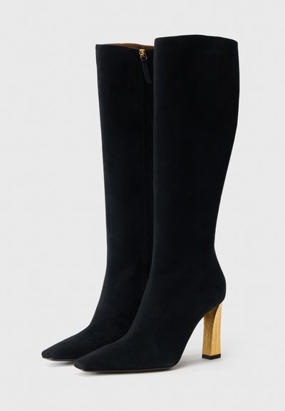 Fekete szarvasbőr térdig érő csizma hegyes orral és aranyozott blokksarkúval. Oldalsó cipzárral rendelkezik a könnyű felvétel érdekében.