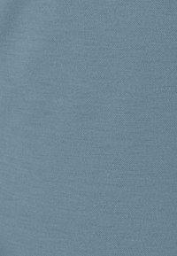 Tela de algodón azul claro con una textura suave, que presenta un patrón de punto uniforme. No hay acentos ni herrajes notables.