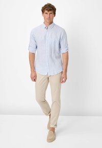 Blauw-wit gestreepte overhemd met knopen, opgerolde mouwen, gecombineerd met beige broeken en lichtbruine instappers. Eenvoudig ontwerp, casual pasvorm.
