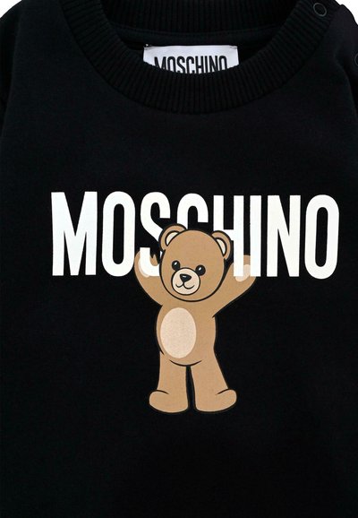 Felpa nera con grafica di un orso bruno con le braccia sollevate e la scritta "MOSCHINO" in lettere bianche in grassetto sopra. Tessuto morbido.