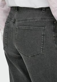 KÕRGEMALT TOODUD HALLID DENIMI JEANSID, MIS OMAVAD SILET TEKSTUURI, KAHET TAGAKÜLJE TASKUT JA ÕRNALT FADINUD VÄLJANÄGEMIST. ÕMBLIKUD ON KERGIS KUIDAS SEERUMITE JUURES NÄHA.