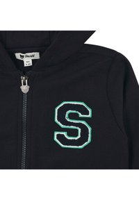 Schwarze Zip-Hoodie mit gerippter Textur, ausgestattet mit einem gestickten Buchstaben "S" in Marineblau und grünen Akzenten sowie einem Bären-förmigen Reißverschluss-Anhänger.