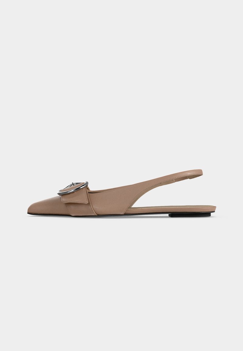 Μπεζ γυναικείο flat slingback παπούτσι με μυτερή μύτη, διακοσμητική ασημένια αγκράφα μπροστά και χαμηλό μαύρο τακούνι.