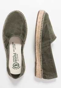 Espadrillas verdi in cotone con suola in juta, caratterizzate da punta chiusa e dettagli cuciti lungo il bordo. Materiali ecologici utilizzati.