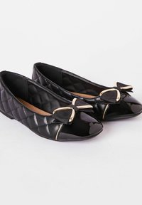 Bailarinas negras acolchadas con un acabado brillante, que presentan un lazo decorativo y detalles en tono dorado en la puntera. Suave forro interior.