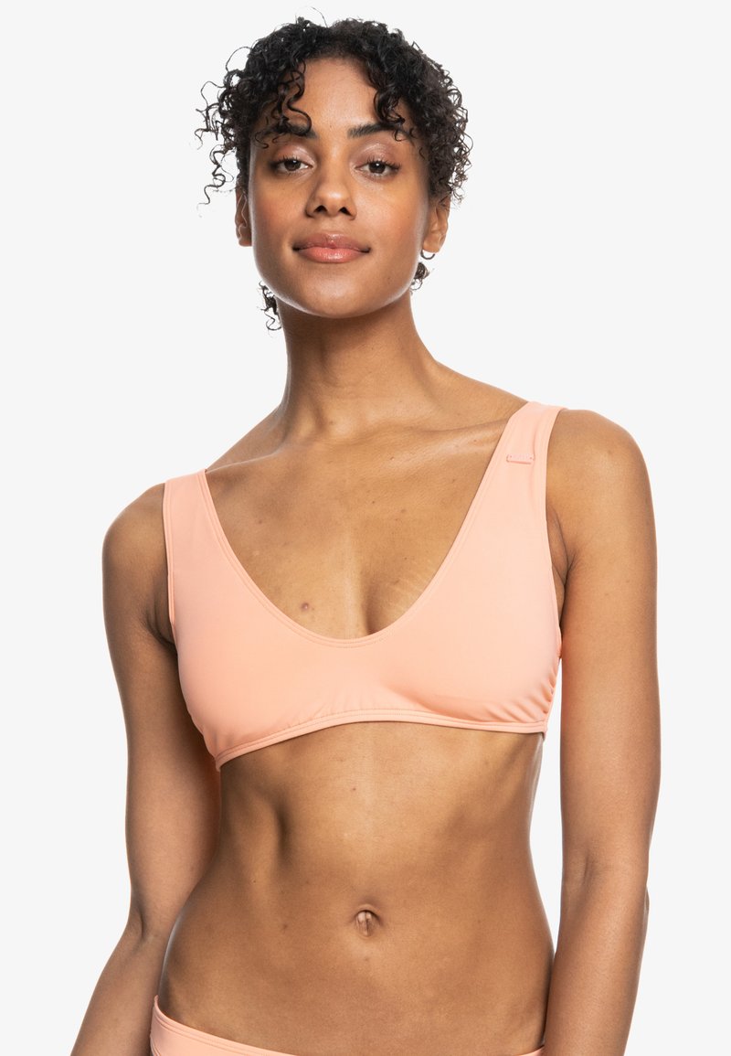 Perzikkleurige bikinitop met een diepe V-hals, brede banden en een soepel, rekbaar materiaal. Beschikt over minimale stiksels en een subtiele logodetail.