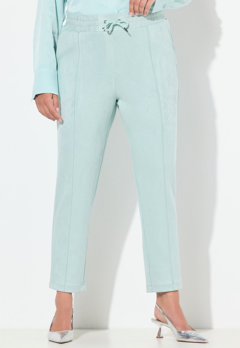 Light mint green jogger pants in soft, suede-like fabric with an elastic waistband and adjustable drawstring, featuring side pockets and straight legs.