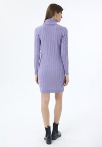 Strickkleid in Helllila mit hohem Kragen, das über ein strukturiertes Zopfmuster und eine figurbetonte Silhouette verfügt, die bis zur Oberschenkelmitte reicht.