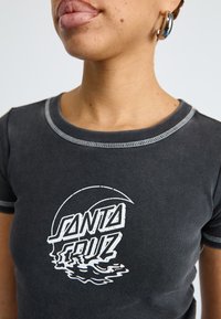 T-shirt ajustada de algodão preto com mangas curtas, apresentando um gráfico branco "SANTA CRUZ", decote redondo e detalhes de costura em contraste.