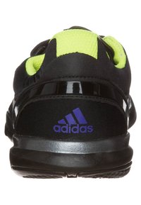Czarne buty sportowe z zielonymi akcentami, teksturowaną tkaniną i błyszczącym czarnym oplotem na pięcie. Na butach znajduje się fioletowe logo Adidas.