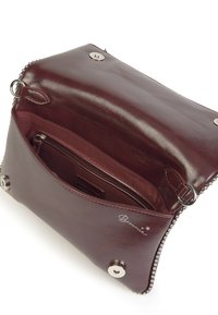 Bolso de cuero marrón con una textura suave, compartimento con cremallera en el interior y detalles metálicos. Presenta un cierre de presión y un detalle de cadena en los bordes.