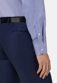 Blå och vit rutad skjorta med knäppte manschetter, matchad med marinblå strukturerade byxor och ett svart bälte med en stilren finish.