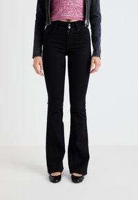 Black flared jeans made of cotton blend, featuring a high waist, two front pockets, and a smooth texture. Paired with a cropped top.