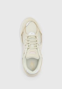 Light beige athletic shoe with a mesh upper and suede accents, featuring a reflective silver logo and pink detailing on the side.