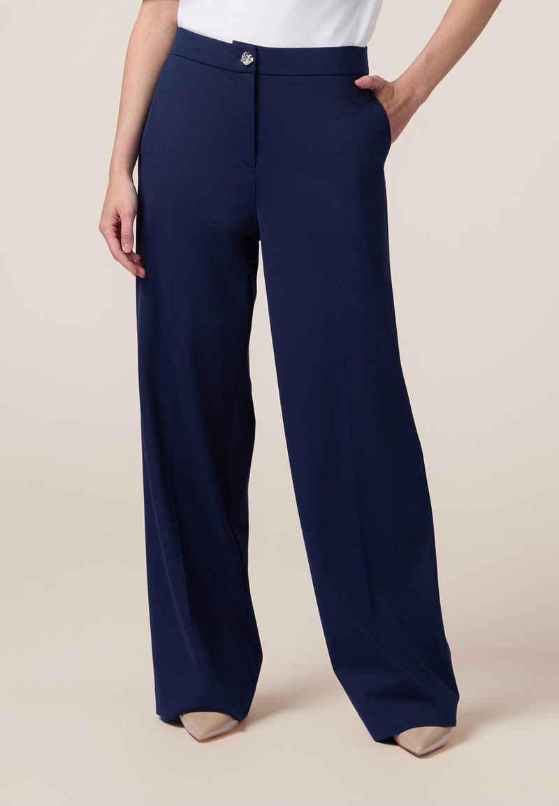 Marina vida byxor med vida ben, gjorda av en slät tyg, med dragkedja och knappstängning, sidfickor och skräddarsydd siluett.