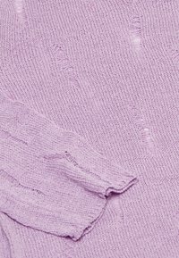 Maglione a maglia di un leggero colore viola con un motivo testurizzato e bordi sfrangiati. Il tessuto sembra morbido e presenta variazioni di densità in tutto il capo.