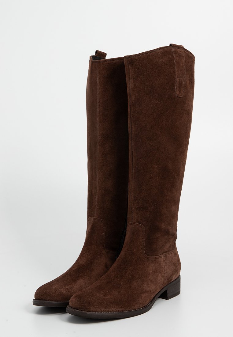 Para wysokich, ciemnobrązowych zamszowych botków z niskim obcasem i pętlami, stojących wyprostowanych na białym tle.