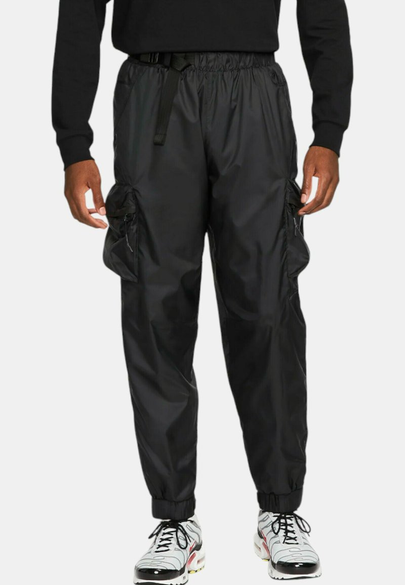 Svarta, lätta cargobyxor i nylon med elastiska muddar och midja. Har två sidofickor och justerbart bälte. Slät textur.