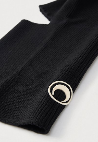 Melnas, ribveida adītas piedurknes ar lielu baltu pusmēness logotipu aprocē. Auduma tekstūra ir maiga, ar atvērtu dizainu īkšķa vietā.