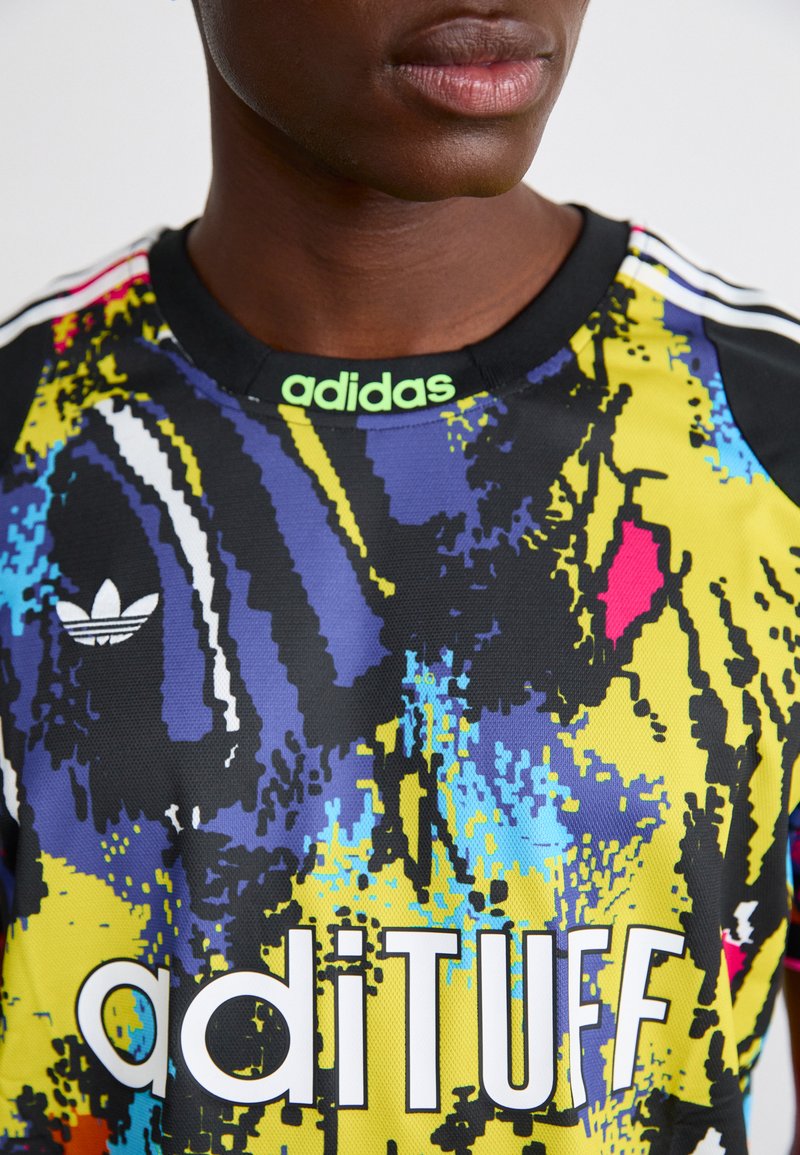 Barevný sportovní dres adidas s živým abstraktním vzorem v žluté, modré a černé barvě, s bílým logem a textem "aditUFF."