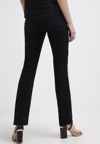 Svarta, slim-fit byxor med en slät yta, bakfickor och raka ben. Tillsammans med bruna klacksandaler med blockklack.