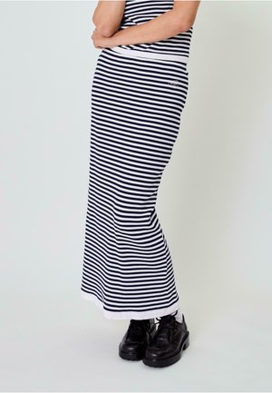 Navy- und weiße gestreifte Rippkleid mit einer figurbetonten Silhouette, ausgestattet mit einem weißen Saum und kombiniert mit schwarzen klobigen Schuhen.