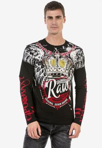 Schwarzes Langarmshirt mit weißen und roten Grafiken, das ein Kronen-Design und Flügeldetails zeigt. Baumwollmischung, figurbetonter Schnitt.