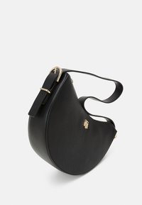 Sac en cuir noir au design courbé, avec des détails en métal doré, une bandoulière ajustable et une fermeture éclair. Surface texturée avec un logo en relief.