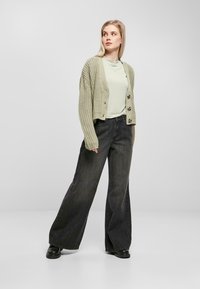 Ljusgrön kortärmad topp, överdimensionerad beiga stickad cardigan och vida svarta jeans. Svarta ankelstövlar, strukturerad stickning på cardie.