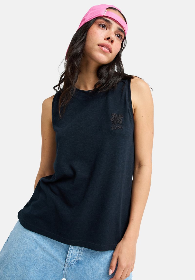 Μαύρο αμάνικο T-shirt με στρογγυλή λαιμόκοψη και διακρ ιτικό λογότυπο λουλουδιού. Συνδυασμένο με ανοιχτό γαλάζιο τζιν, με άνετη εφαρμογή και λεία υφή.