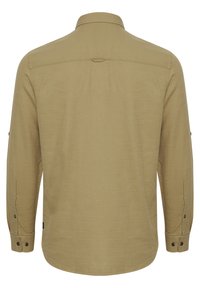 Chemise à manches longues en khaki avec une texture lisse, un col classique et des poignets boutonnés. Présente un empiècement et un ourlet arrondi.