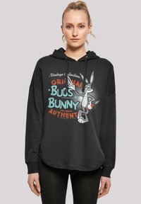 Čierna mikina s uvoľneným strihom, s vintage grafikou Bugs Bunny v tyrkysovej a červenej farbe. Detail s šnúrkami pri kapucni a rebrované manžety.