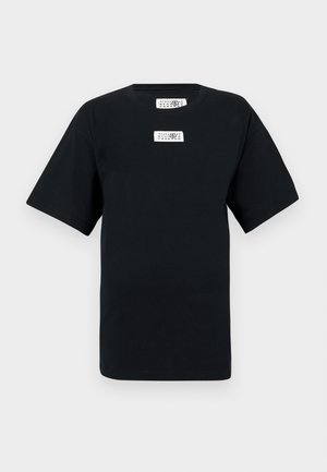 T-shirt preta de algodão com mangas curtas, gola redonda, apresenta duas etiquetas brancas no peito. Design simples, corte regular, sem padrões ou acentos.