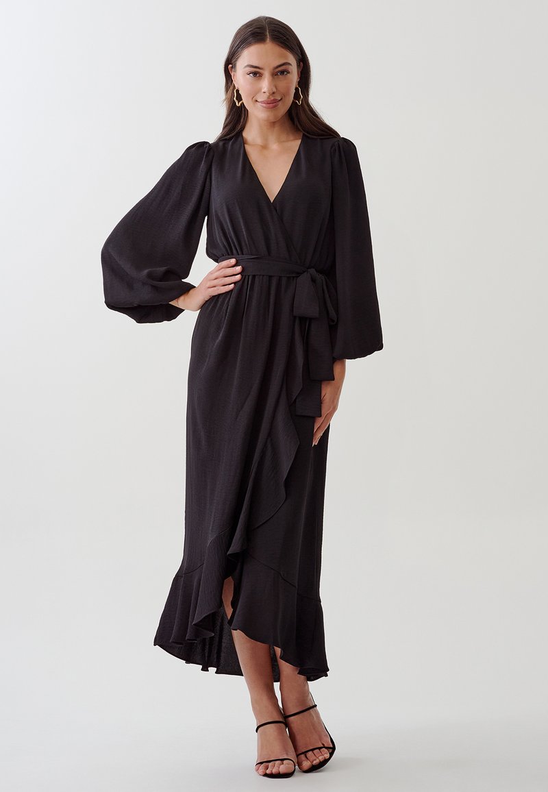 Robe noire à manches bouffantes en tissu léger, avec une taille nouée, un ourlet rufflé et un décolleté en V profond.
