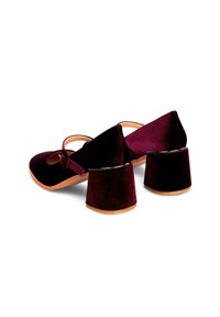 Zapatos de terciopelo burdeos con puntera redonda, correa al estilo Mary Jane y tacones cuadrados que presentan un suave acento negro. Suela plana.
