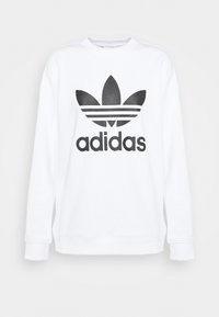 Vit sweatshirt i bomull med långa ärmar, utrustad med en svart Adidas-logotyp och tre horisontella ränder under logotypen.