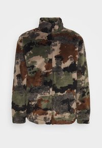Fleecejakke i en camouflagemønster med grønne, brune og sorte nuancer. Høj krave og lynlås lukning, blød tekstur overalt.