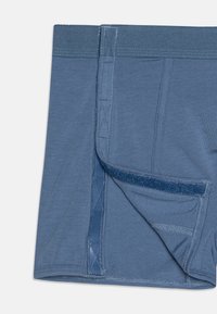 Boxers de tejido azul con una cinturilla suave, costuras planas y un cierre de gancho y bucle en la parte frontal para un fácil acceso.