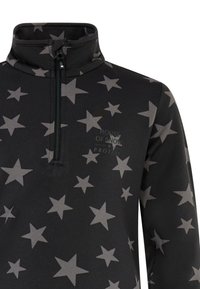 Haut en polaire noir avec un motif d'étoiles grises, col zippé à mi-hauteur et logo "Maison de la Neige" imprimé en gris sur le devant. Tissu doux et texturé.