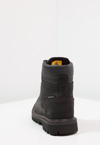 Botín negro impermeable hasta el tobillo con cuero texturizado, cuello acolchado y suela de goma resistente; presenta logotipo y acentos de costura.