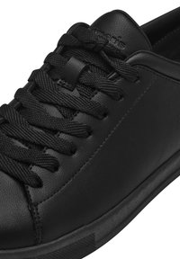 Schwarze Leder-Sneaker mit flachen schwarzen Schnürsenkeln, glatter Oberfläche, minimalistischer Gestaltung und einer dunklen Gummisohle mit dezentem Muster.